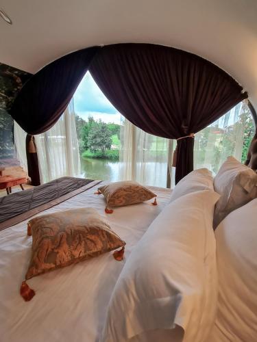 a bedroom with a large bed with a large window at AKIS namelis medyje- Dinosaur Park in Radailiai
