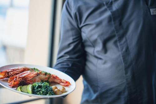 a person holding a plate of seafood and vegetables at La Mer Resort Spa Crete in Georgioupolis