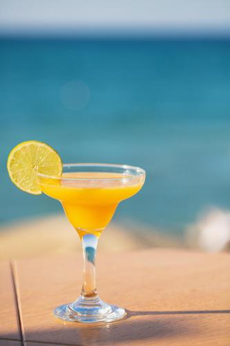 a glass of orange juice with a lime on a wooden table at La Mer Resort Spa Crete in Georgioupolis