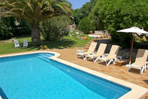 a swimming pool with lounge chairs and an umbrella at Las Tórtolas in Alaior
