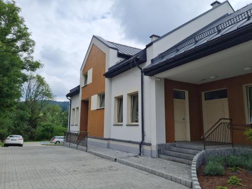 a house with a car parked in front of it at Apartamenty Pod Dachem in Lutowiska