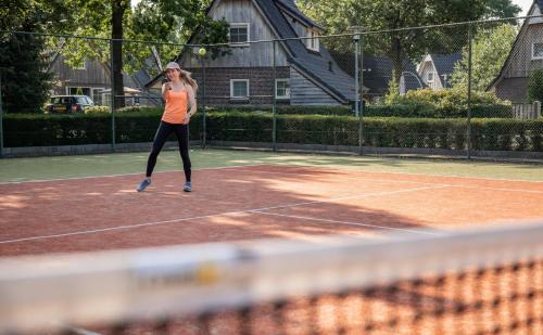 a woman is playing tennis on a tennis court at Hof van Salland Hellendoorn in Hellendoorn