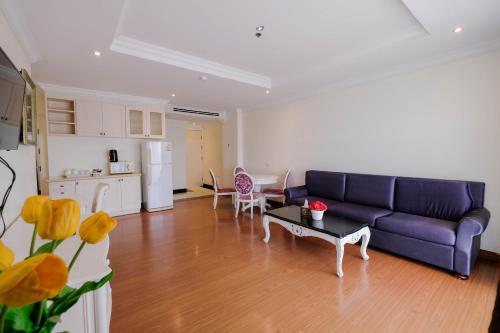 a living room with a blue couch and a kitchen at LK Miracle Suite - SHA Extra Plus in Pattaya South