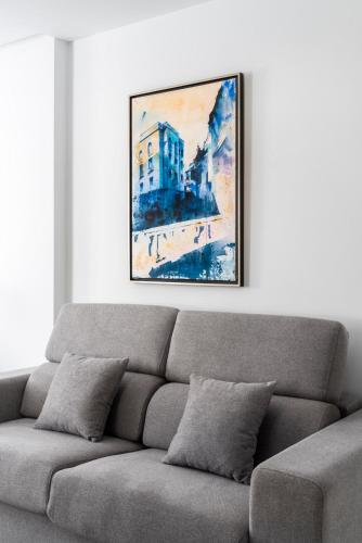 a couch in a living room with a painting on the wall at Apartamentos Casa del Arco de 2 a 6 personas in Andújar