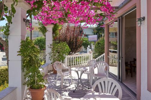 un patio con sillas y una mesa con flores rosas en Apollon Hotel Apartments, en Platanes
