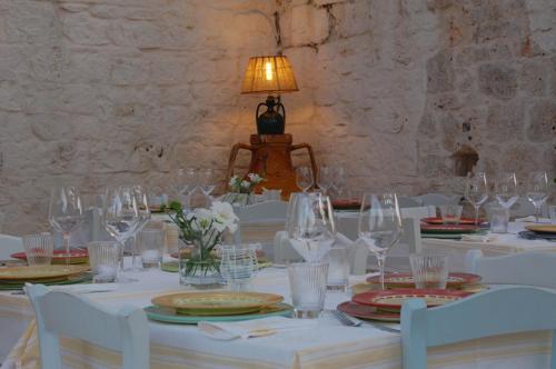 a table with white chairs and wine glasses at Masseria Cervarolo in Ostuni