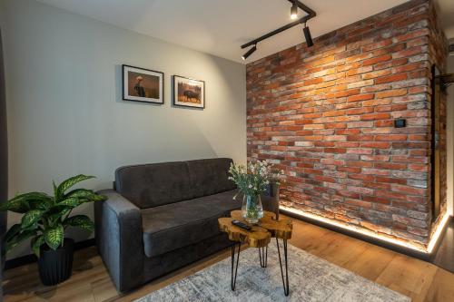 a living room with a couch and a brick wall at Bison Apartamenty in Białystok