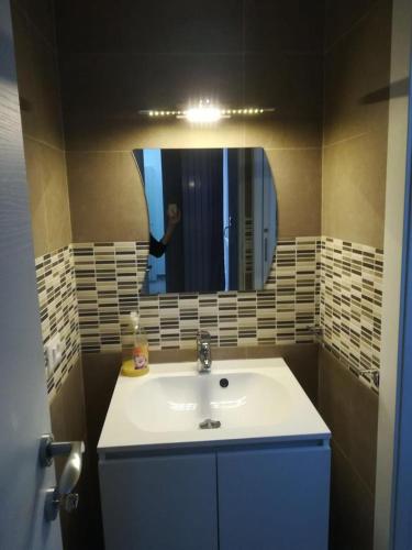ein Badezimmer mit einem Waschbecken und einer Person im Spiegel in der Unterkunft Berenice Suite in Taranto