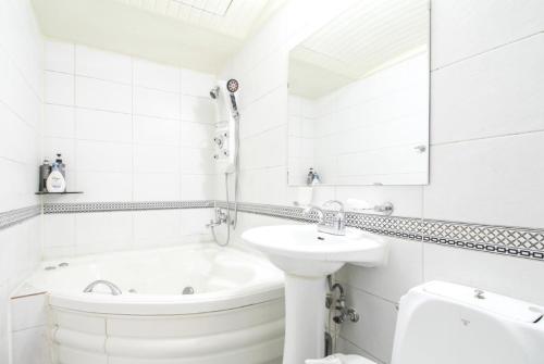 a white bathroom with a sink and a bath tub at Couple Motel in Seoul