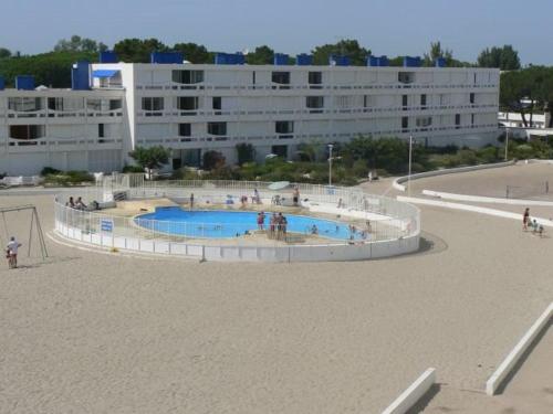 un immeuble avec une piscine devant un immeuble dans l'établissement Appartement 2 pièces avec piscine et parking, en bord de plage - FR-1-250-213, au Grau-du-Roi
