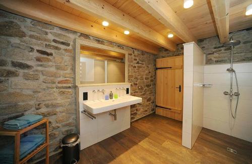 La salle de bains est pourvue d'un lavabo et d'un mur en pierre. dans l'établissement Exenbacher Hof Traumbauernhaus s´Haisl, à Arnbruck