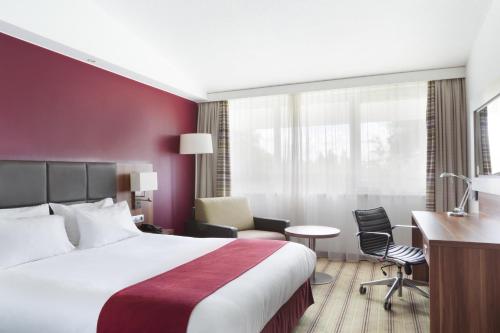 a hotel room with a bed and a desk at Holiday Inn Lille Ouest Englos, an IHG Hotel in Englos