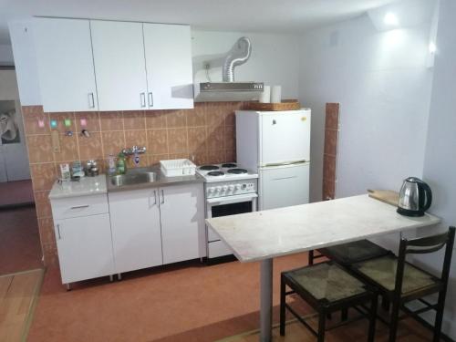 a kitchen with white cabinets and a table and a refrigerator at Apartman Oaza Olja in Belgrade