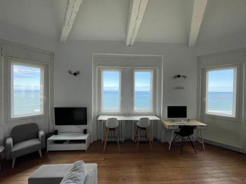 - un salon avec trois fenêtres, une table et des chaises dans l'établissement 1ère ligne Mer Appartement 7 personnes., à Biarritz
