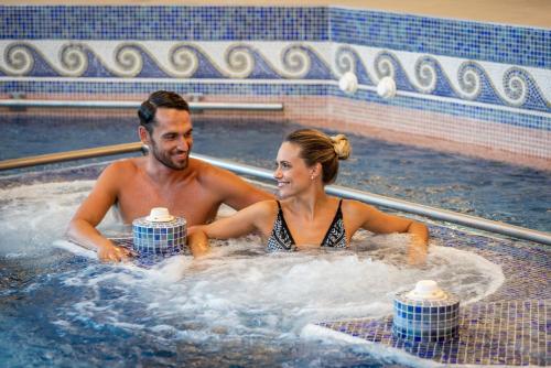 a man and a woman sitting in a hot tub at Grand Hotel Terme & Spa in Montegrotto Terme