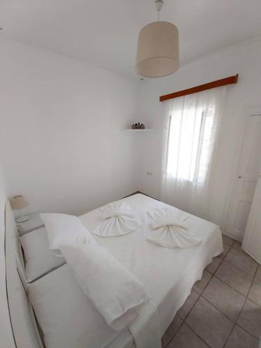 a white bed in a white room with a window at Rosolio in Ano Syros
