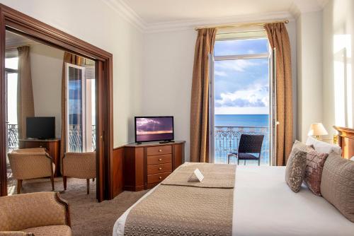 a hotel room with a bed and a view of the ocean at Hôtel West End Promenade in Nice