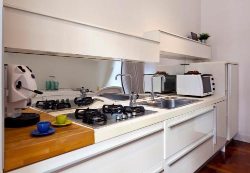 Biała kuchnia z kuchenką i zlewem w obiekcie Elegant Apartment at Chiaia by Wonderful Italy w mieście Napoli