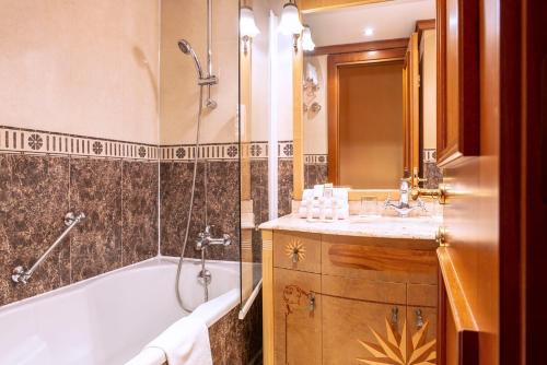 a bathroom with a tub, sink and mirror at Hôtel West End Promenade in Nice