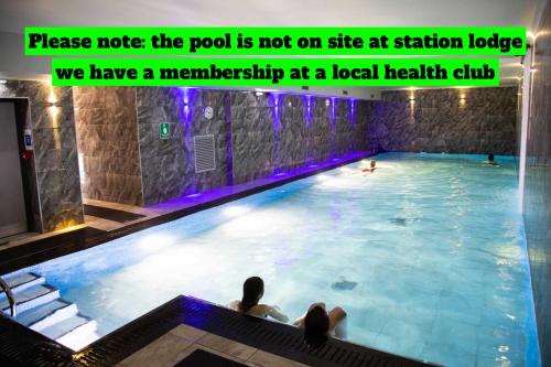 a swimming pool with two people sitting in the water at Station Lodge - FREE off-site Health Club access with Pool, Sauna, Steam Room & Gym in Windermere