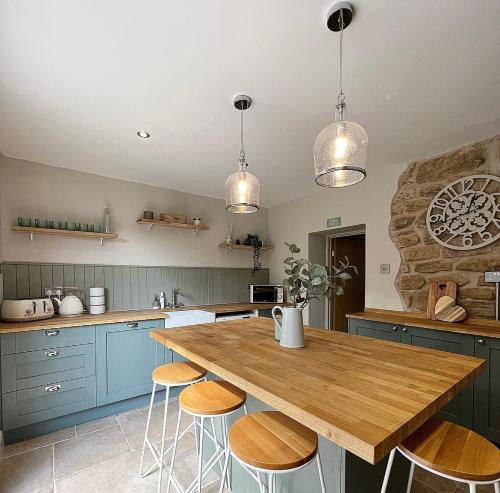 a kitchen with blue cabinets and a wooden table with stools at Mulberry House - Morpeth Town Centre - Hot Tub in Morpeth