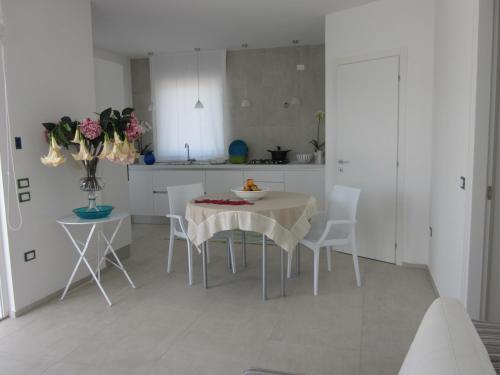 - une cuisine blanche avec une table et des chaises blanches dans l'établissement La scogliera, à Petrosino