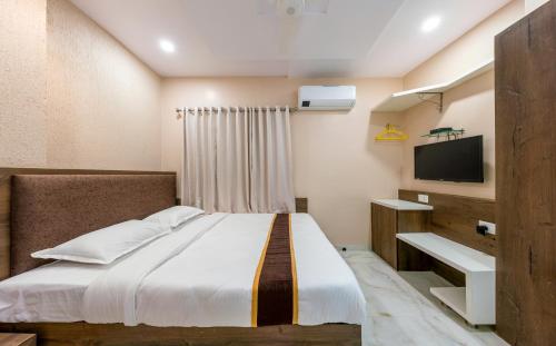 a bedroom with a bed and a flat screen tv at Hotel Aatithya Satkar Near Mahalaxmi Temple in Kolhapur