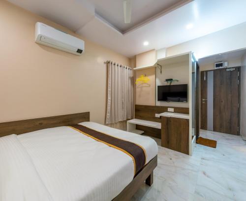 a bedroom with a bed and a sink and a tv at Hotel Aatithya Satkar Near Mahalaxmi Temple in Kolhapur