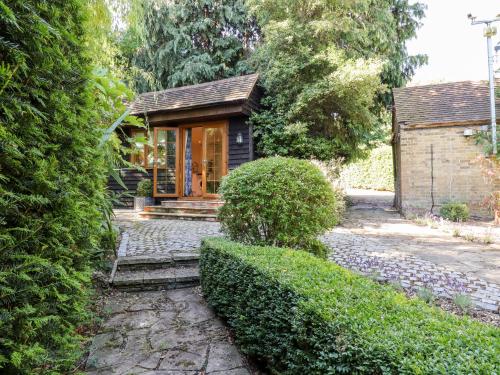 a small house in a garden with bushes at Willow Cottage in Dartford