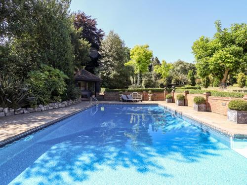 a swimming pool with blue water in a yard at Willow Cottage in Dartford