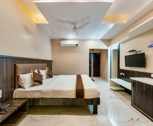 a bedroom with a bed and a flat screen tv at Hotel Aatithya Satkar Near Mahalaxmi Temple in Kolhapur