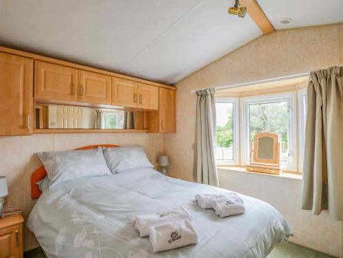 a bedroom with a large bed with towels on it at Ty Newydd Caravan in Pwllheli