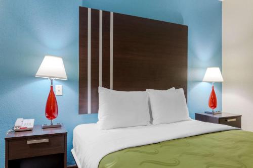 a bedroom with a large bed with two lamps on tables at Quality Inn Columbus-East in Columbus