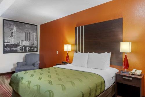 a hotel room with a bed and a chair at Quality Inn Columbus-East in Columbus