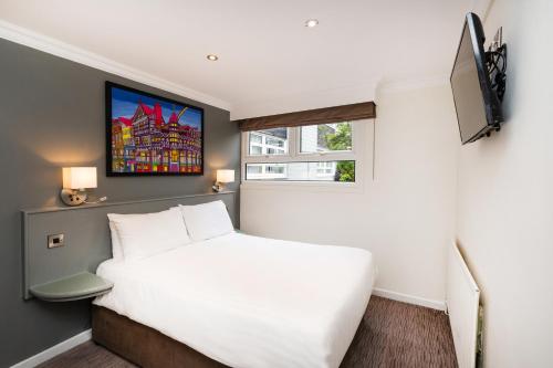 a bedroom with a white bed and a tv at Mercure Chester Abbots Well Hotel in Chester