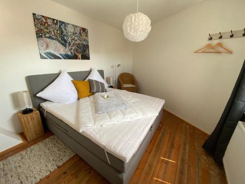 Un dormitorio con una cama con sábanas blancas y una lámpara de araña. en Ferienwohnung "Boddenland" en Barth