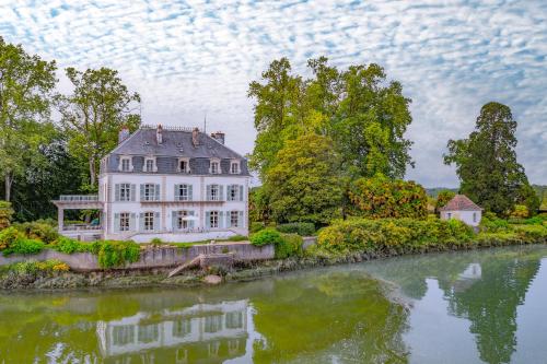 une grande maison blanche située au bord d'une rivière dans l'établissement Chateau du Bec du Gave, à Port-de-Lanne