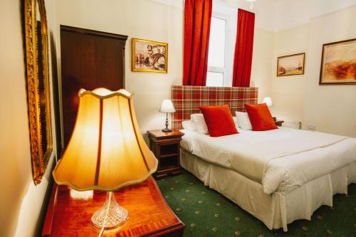 a bedroom with two beds and a lamp on a table at The Town House in Douglas