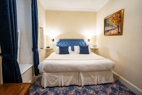 a bedroom with a large bed with blue pillows at The Town House in Douglas