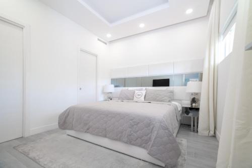 a white bedroom with a large bed and a desk at Luxury 1 bed apartment near Seven Mile Beach at The Grove - Villa Deluxe in Upper Land