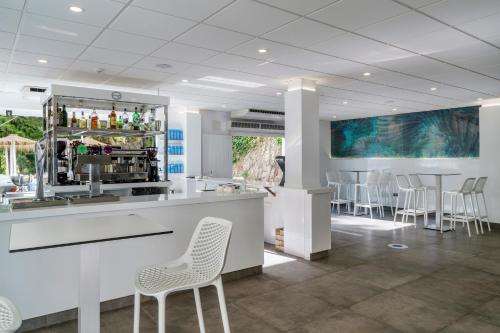 a lobby with a bar with white chairs and tables at AluaSun Costa Park in Torremolinos