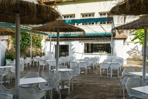 an outdoor restaurant with tables and chairs and umbrellas at AluaSun Costa Park in Torremolinos