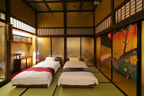 2 Betten in einem Zimmer mit Gemälden an den Wänden in der Unterkunft 飛騨高山浮世絵INN画侖 in Takayama
