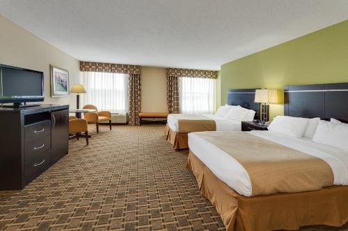 a hotel room with two beds and a flat screen tv at Holiday Inn Statesboro-University Area by IHG in Statesboro