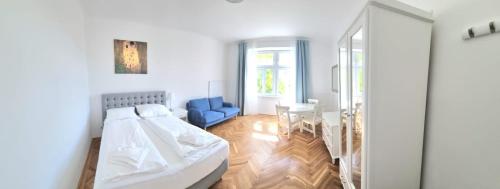 a white room with a bed and a blue chair at Herzlich Willkommen - Küss die Hand 3 in Vienna