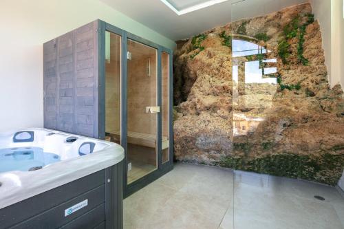 Moundros Luxury Villa & Spa في Moúndros: حمام مع حوض وجدار صخري