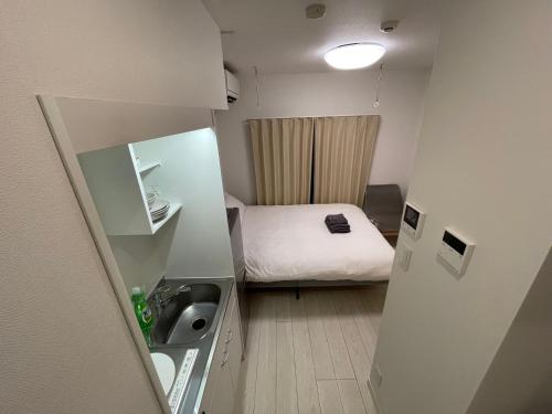 Kleines Zimmer mit einem Bett und einem Waschbecken in der Unterkunft japan house sugamo in Tokio
