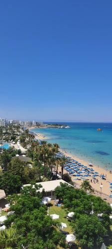 a beach with umbrellas and people in the water at Silver Sands Beach Hotel in Protaras