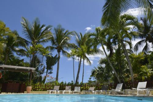 a swimming pool with chairs and palm trees at Hotel - Résidence Habitation Grande Anse in Deshaies