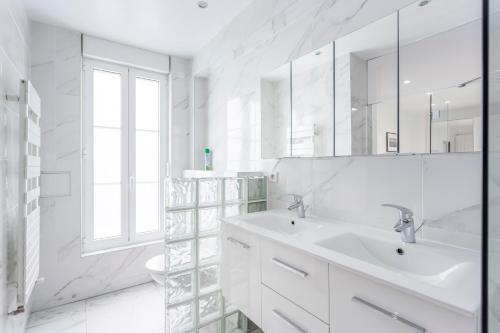 La salle de bains blanche est pourvue d'un lavabo et d'un miroir. dans l'établissement 180 Suite Eden, Luxury APT at Sacré Coeur, à Paris